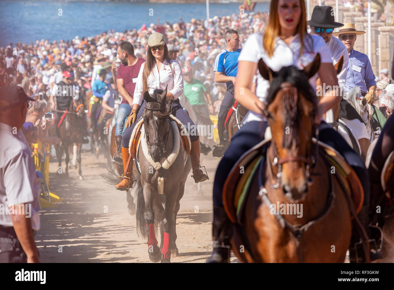 Cavalli e Cavalieri lasciando La Enramada beach dopo la balneazione i loro animali in mare a San Sebastian romeria, fieasta, La Caleta, Tenerife, può Foto Stock