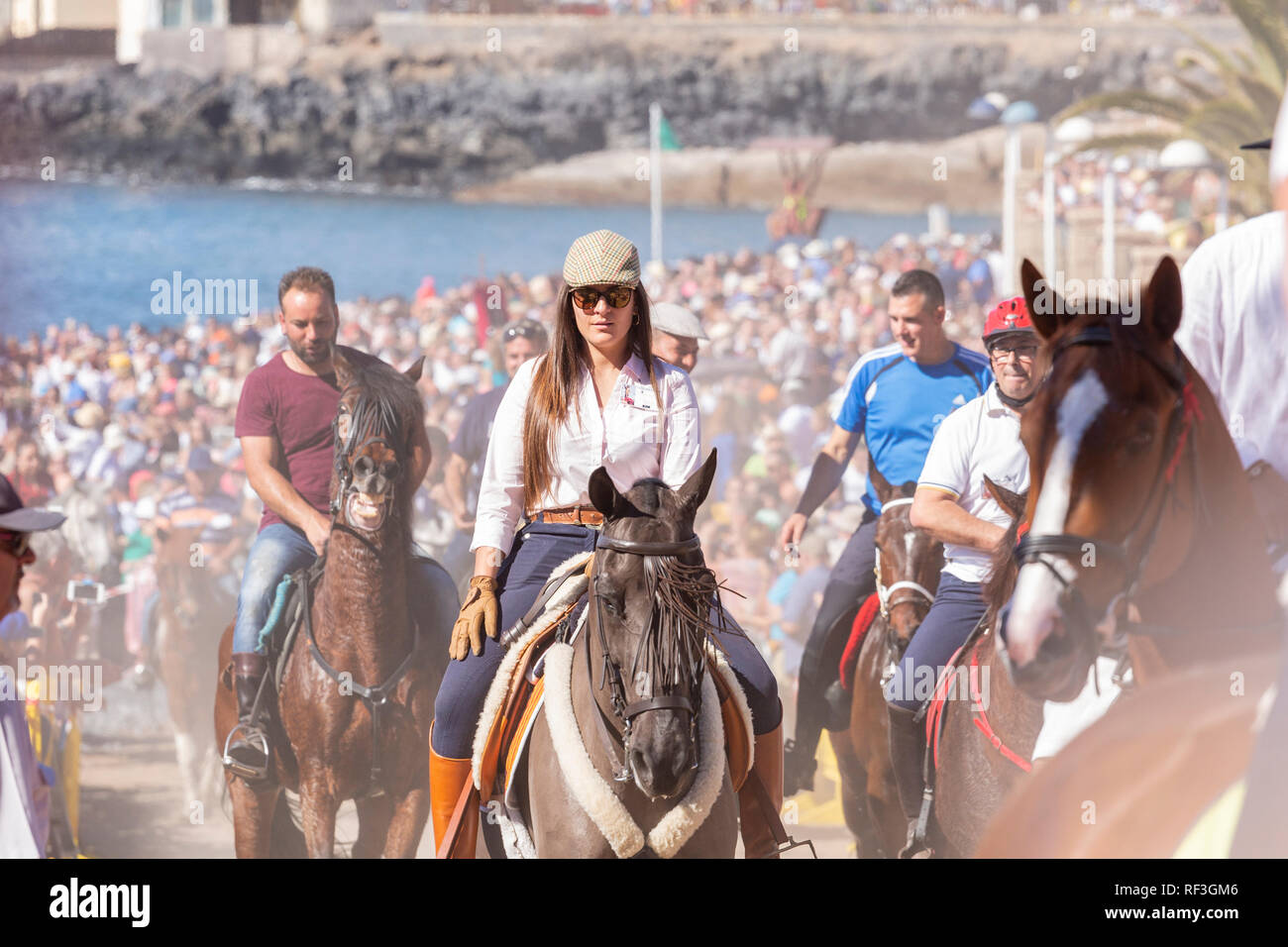 Cavalli e Cavalieri lasciando La Enramada beach dopo la balneazione i loro animali in mare a San Sebastian romeria, fieasta, La Caleta, Tenerife, può Foto Stock
