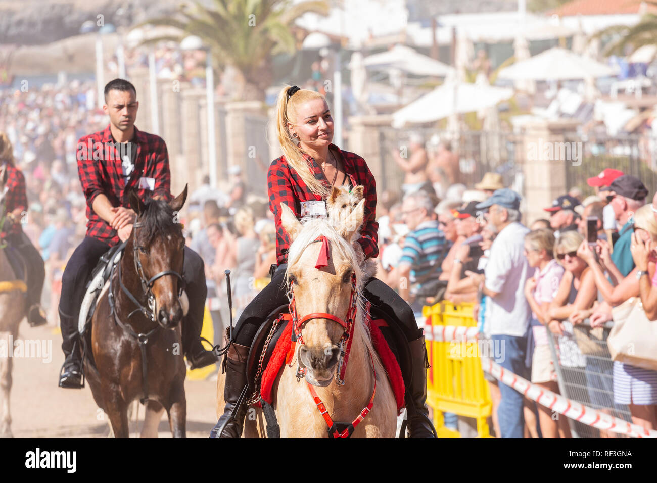 Cavalli e Cavalieri lasciando La Enramada beach dopo la balneazione i loro animali in mare a San Sebastian romeria, fieasta, La Caleta, Tenerife, può Foto Stock