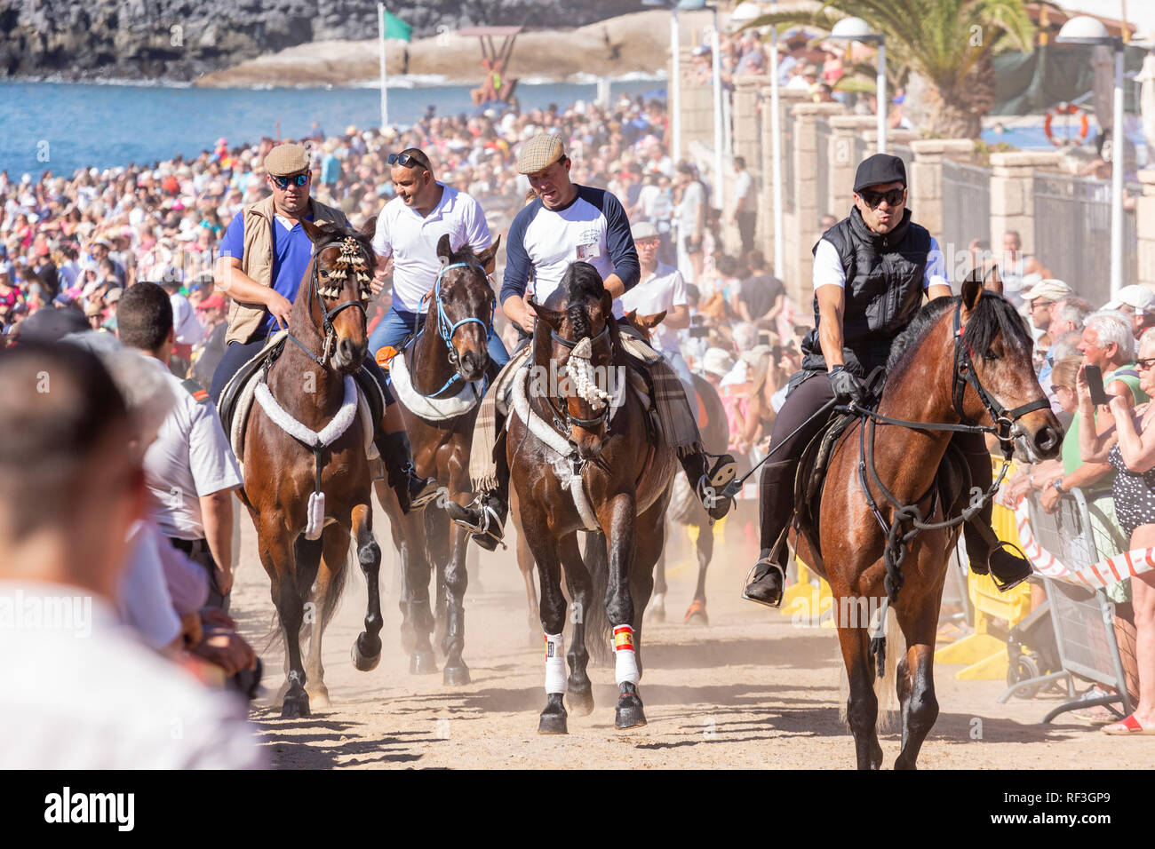 Cavalli e Cavalieri lasciando La Enramada beach dopo la balneazione i loro animali in mare a San Sebastian romeria, fieasta, La Caleta, Tenerife, può Foto Stock