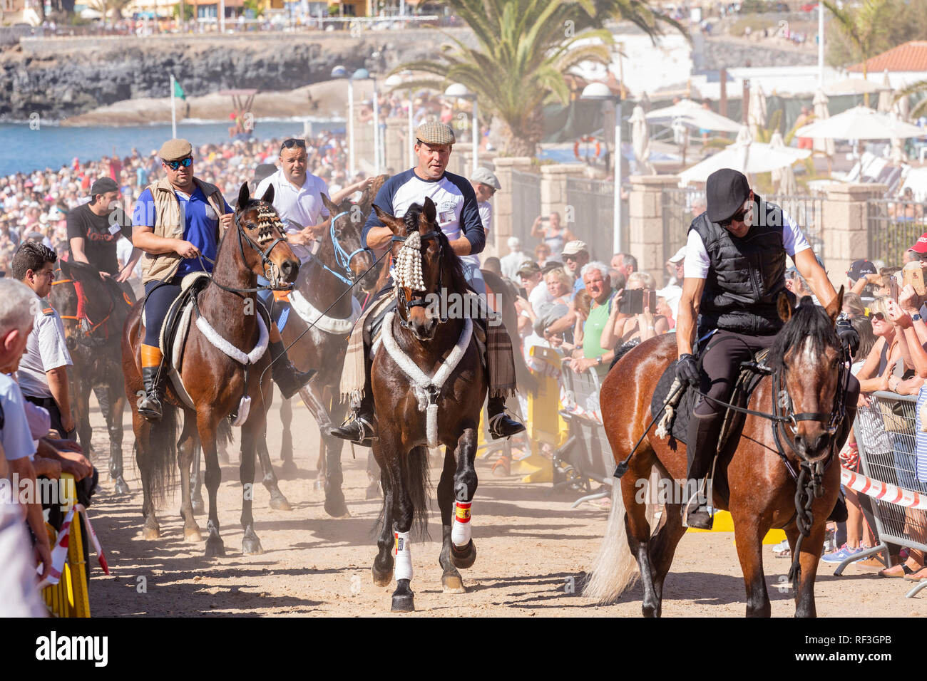 Cavalli e Cavalieri lasciando La Enramada beach dopo la balneazione i loro animali in mare a San Sebastian romeria, fieasta, La Caleta, Tenerife, può Foto Stock