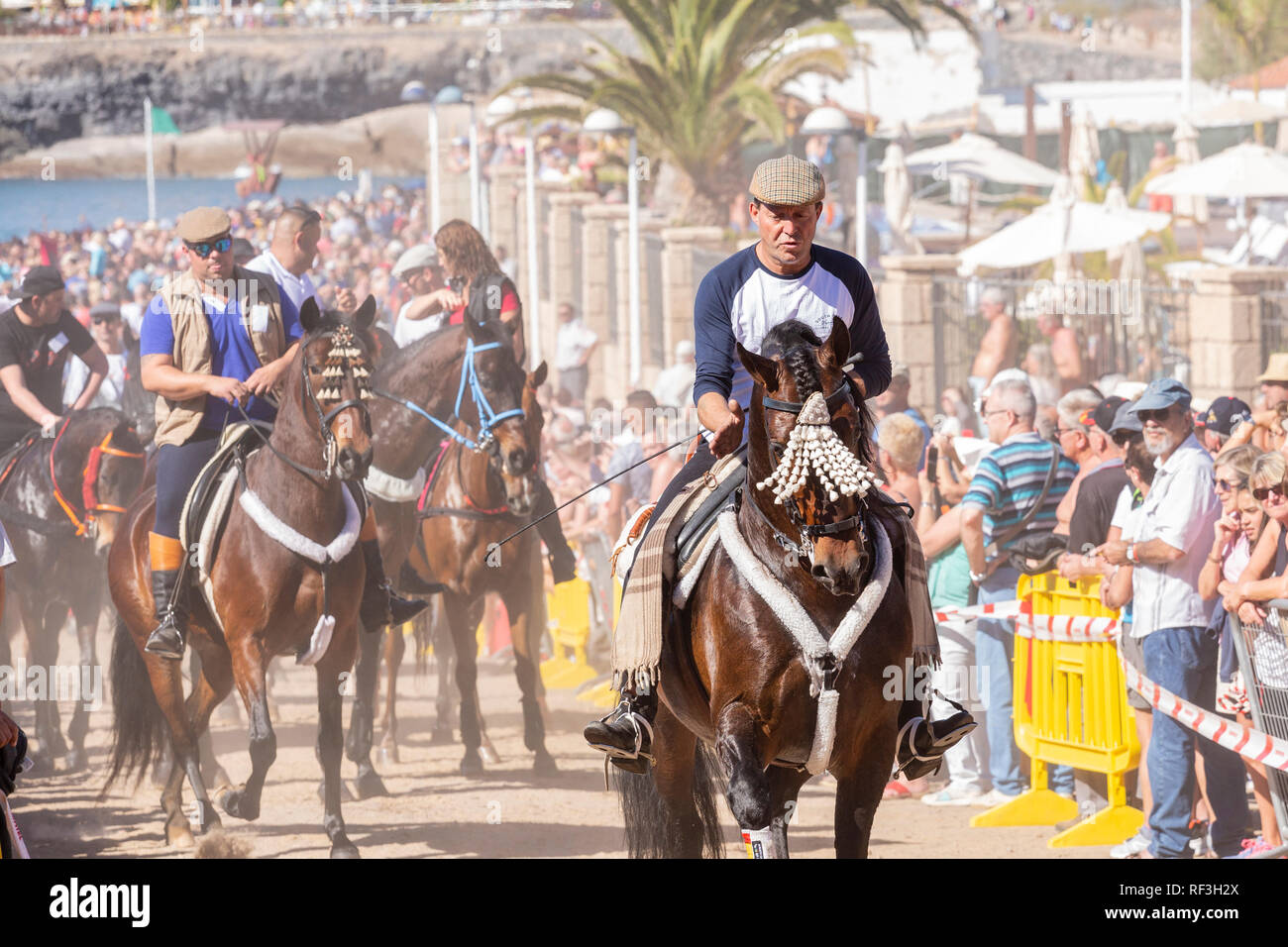 Cavalli e Cavalieri lasciando La Enramada beach dopo la balneazione i loro animali in mare a San Sebastian romeria, fieasta, La Caleta, Tenerife, può Foto Stock