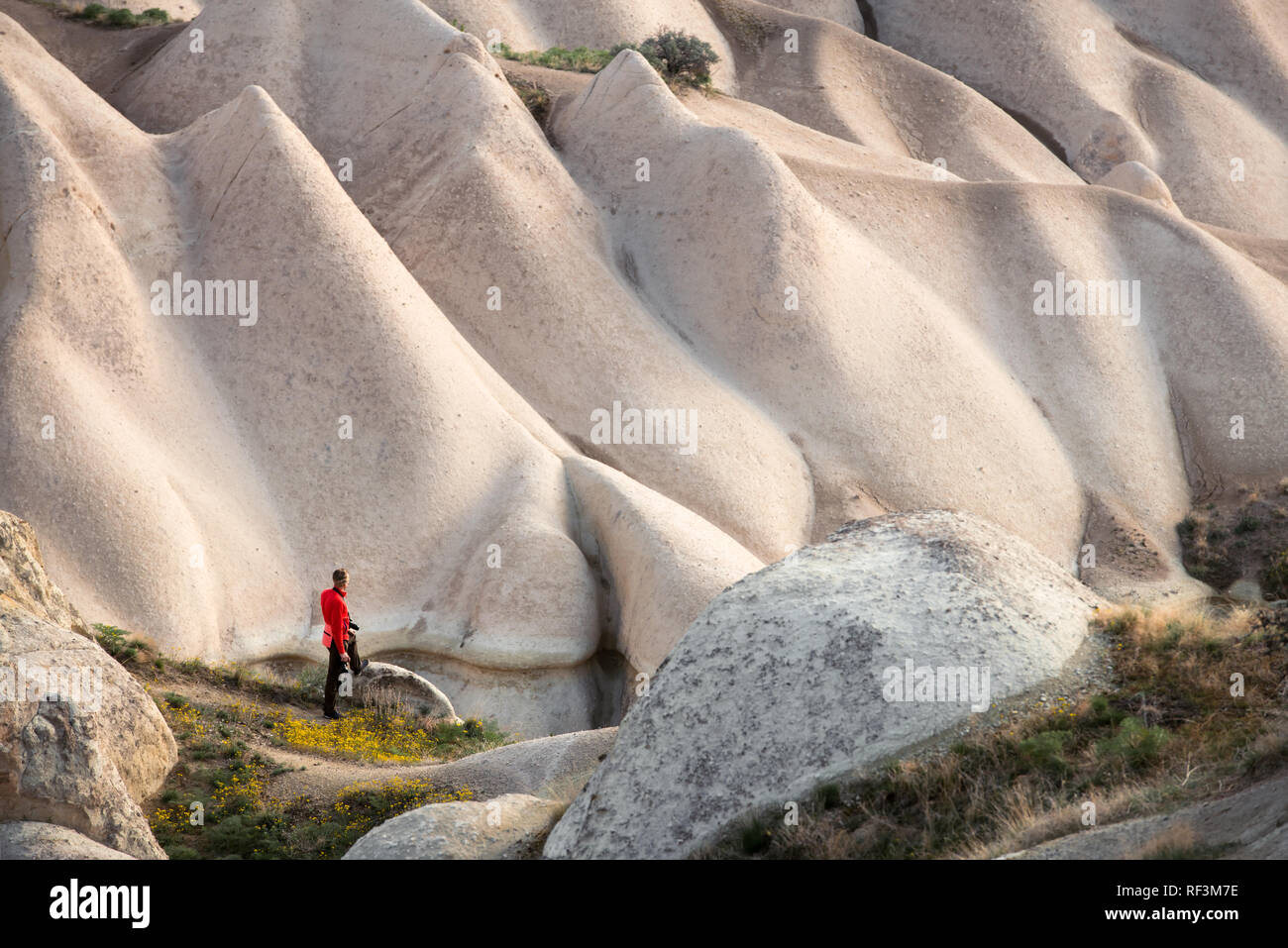 Giornata incredibile in Cappadocia montagne, Turchia. Fotografo in giacca rossa prendendo foto di meravigliose colline. Fotografia di paesaggi Foto Stock