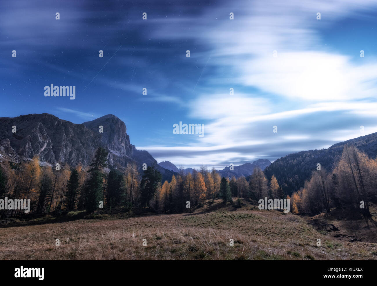 Le montagne in bella notte in autunno nelle Dolomiti, Italia. Paesaggio con alberi in alpine Mountain Valley, prato, il cielo di nuvole, luna e stelle. Foto Stock