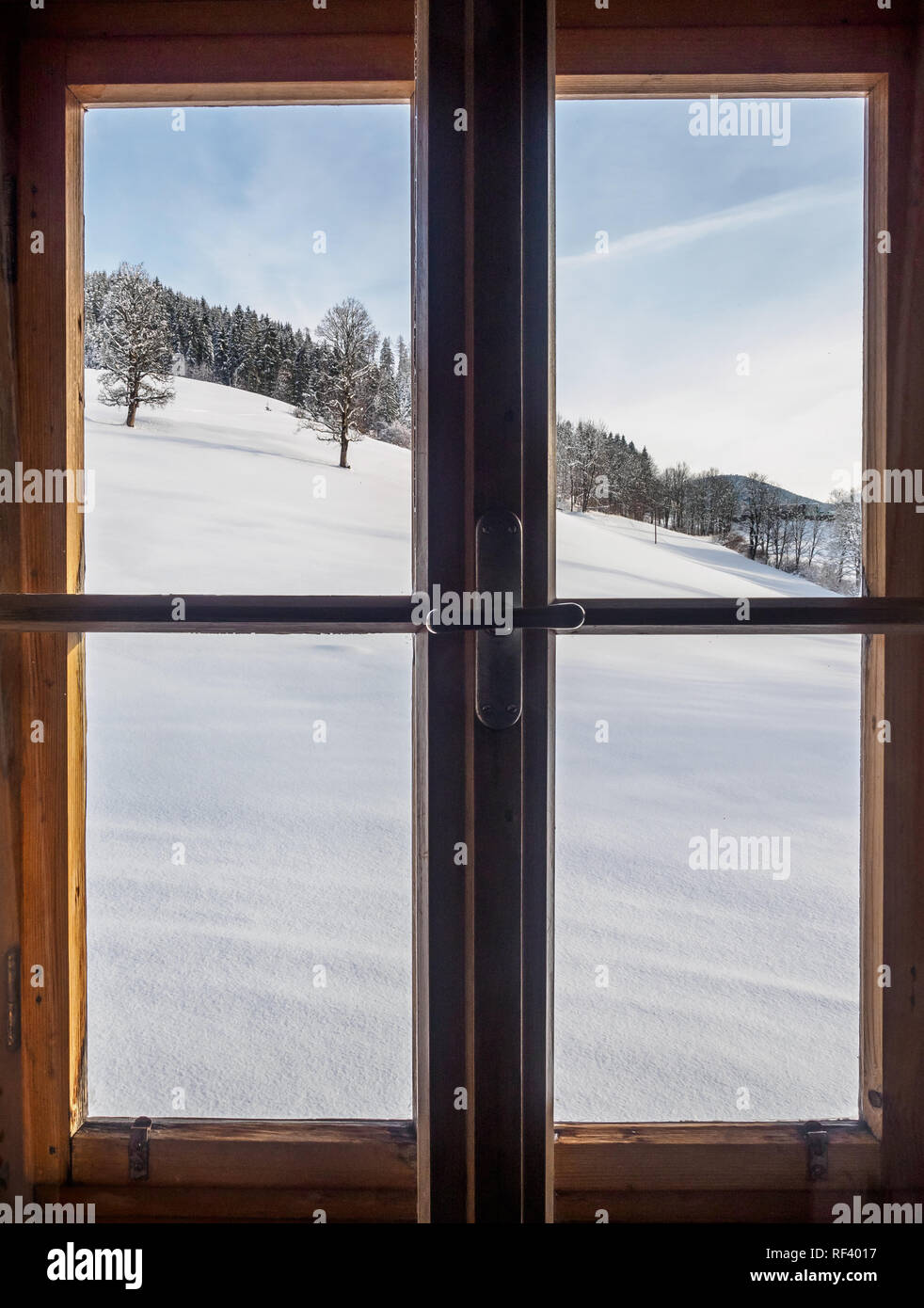 Vista di un inverno austriaco paesaggio visto tramite una finestra di legno in una fattoria Foto Stock