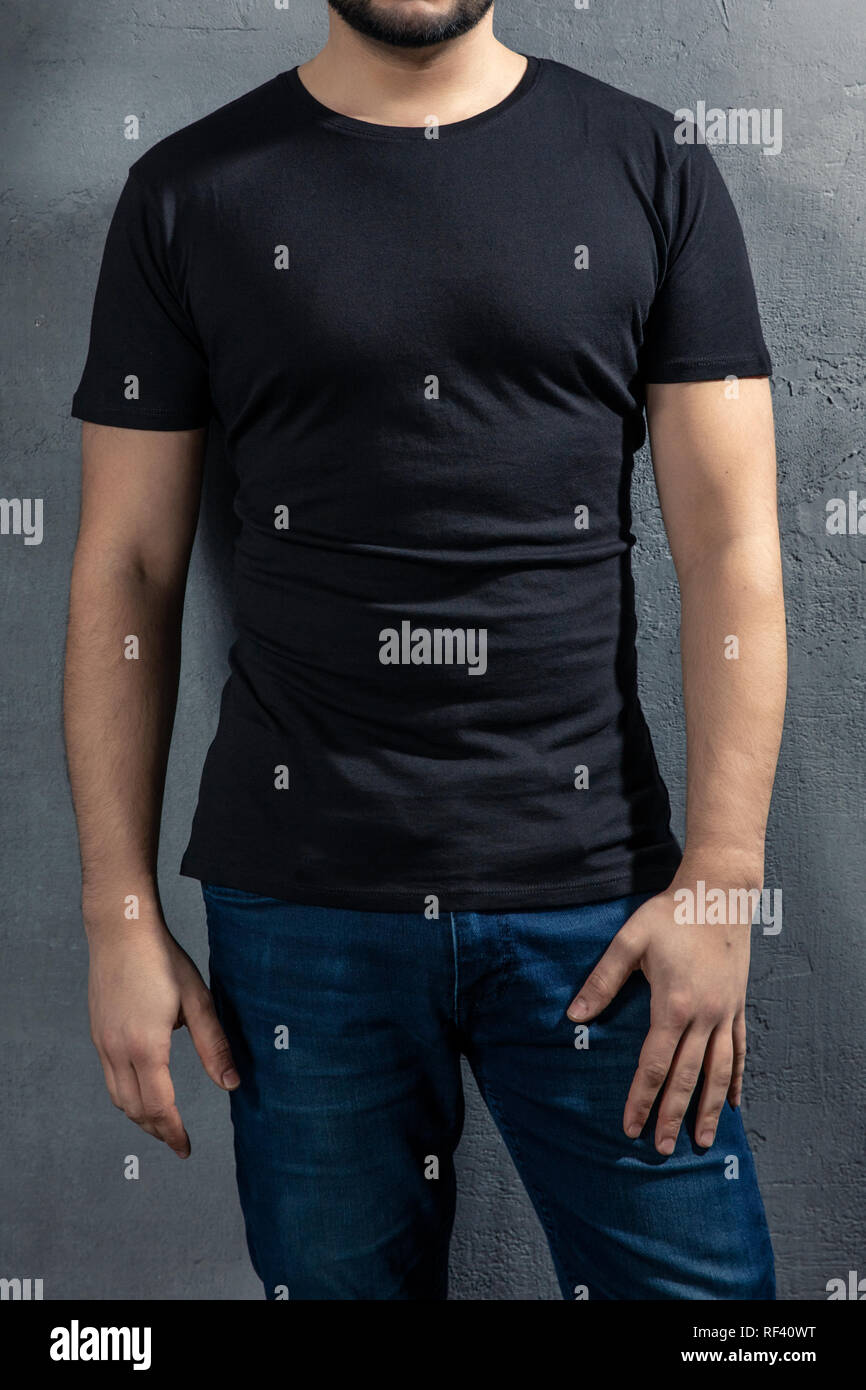 Giovane uomo sano con T-shirt nera su sfondo di calcestruzzo. Immagine modello senza volto. Foto Stock