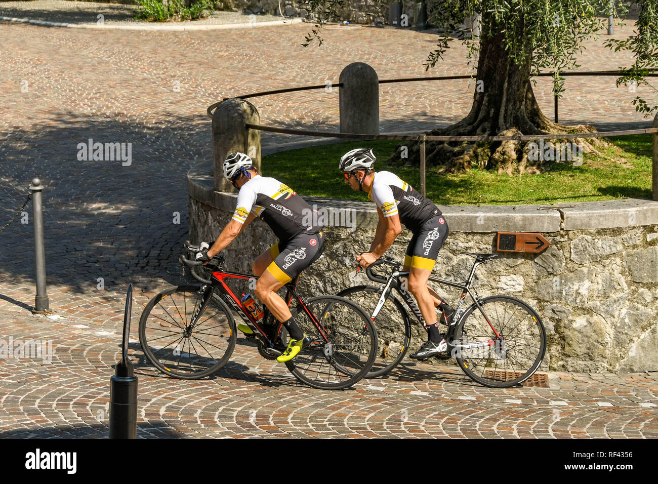 GARDONE RIVIERA, Italia - Settembre 2018: Due ciclisti pedalando su di una ripida collina al di fuori del Vittoriale degli Italiani giardini in Gardone Riviera. Foto Stock