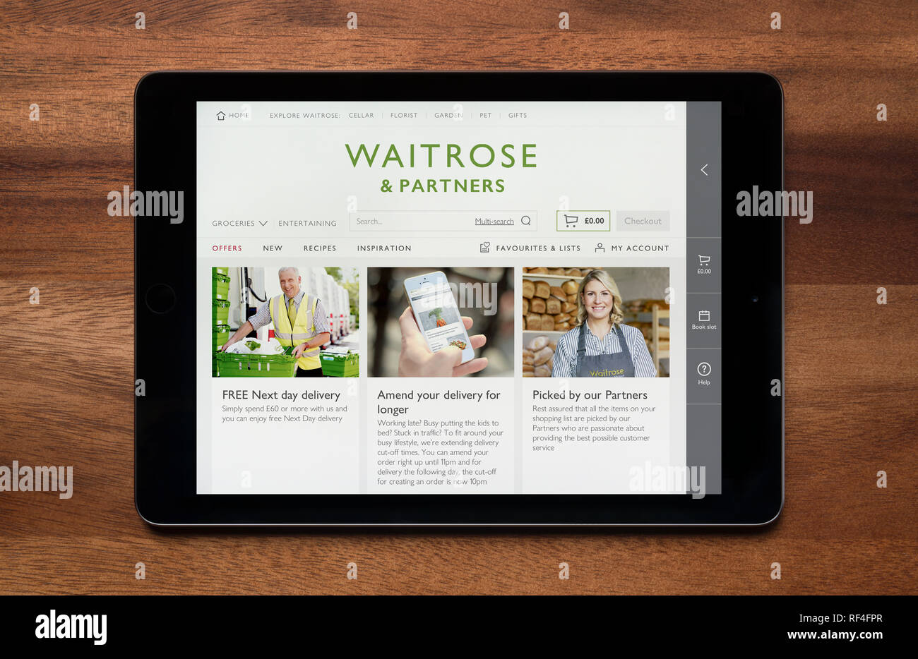 Il sito web di Waitrose e partner è visto su un tablet iPad, il quale è appoggiato su un tavolo di legno (solo uso editoriale). Foto Stock