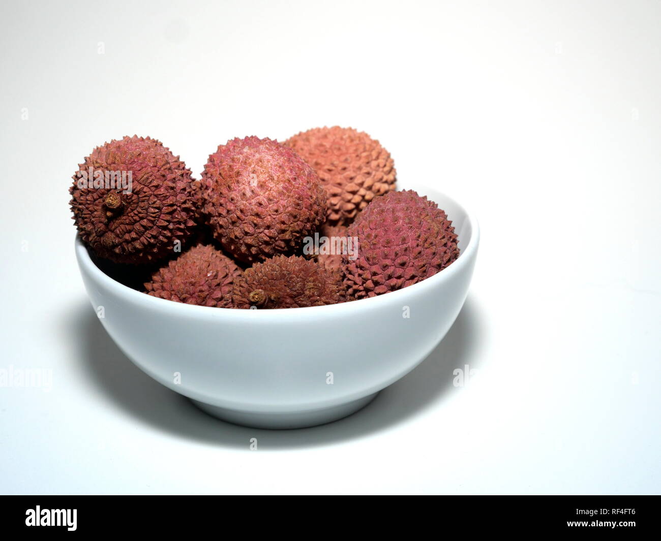 Diversi lychee frutti, in una vaschetta di colore bianco su sfondo bianco Foto Stock