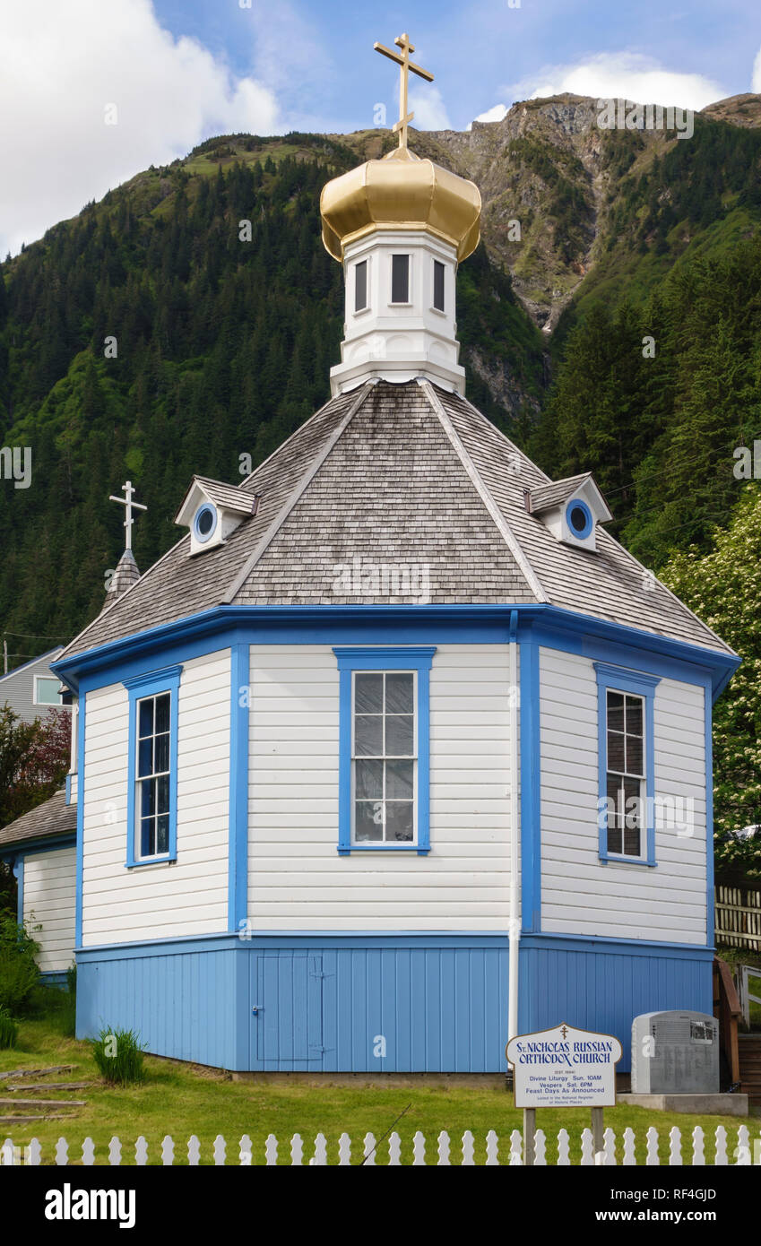Ripidi versanti forniscono uno sfondo drammatico per San Nicola chiesa ortodossa russa, Juneau, in Alaska. Questo storico punto di riferimento presenta una cupola a cipolla. Foto Stock