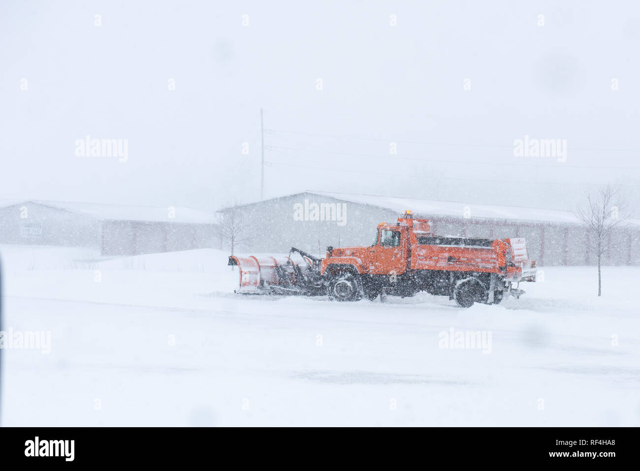 Un aratro di neve la rimozione di neve su una strada durante una bufera di neve. Foto Stock