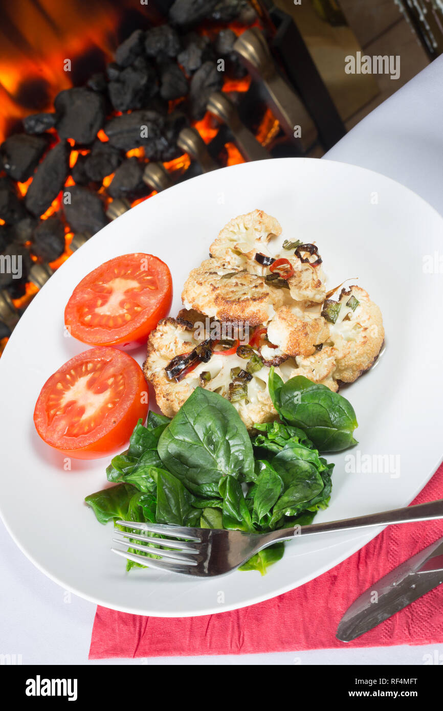 Cavolfiore arrosto di manzo servita con Spinaci appassito e pomodoro grigliate Foto Stock