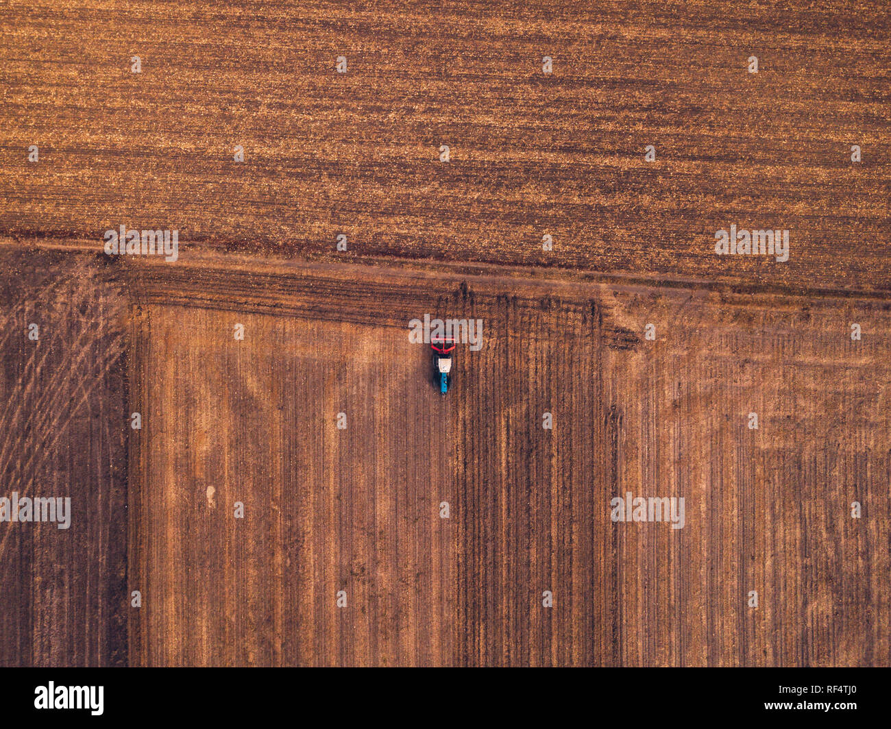 Vista aerea del trattore agricolo facendo dissodamento stoppie nel campo, vista dall'alto da fuco pov Foto Stock