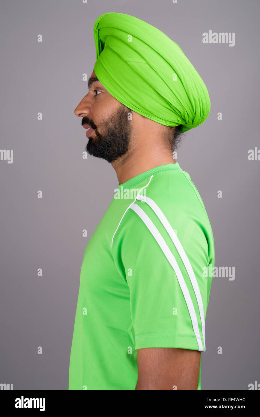 Giovane bello indiano uomo Sikh indossando turbante e camicia verde Foto Stock