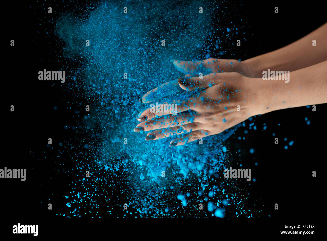 Vista ritagliata della donna adulta azienda blu polvere holi e battendo le mani su sfondo nero Foto Stock