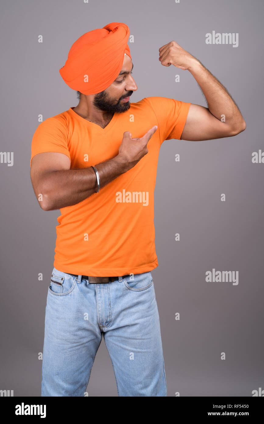 Indiano uomo Sikh indossando turbante e maglietta arancione Foto Stock