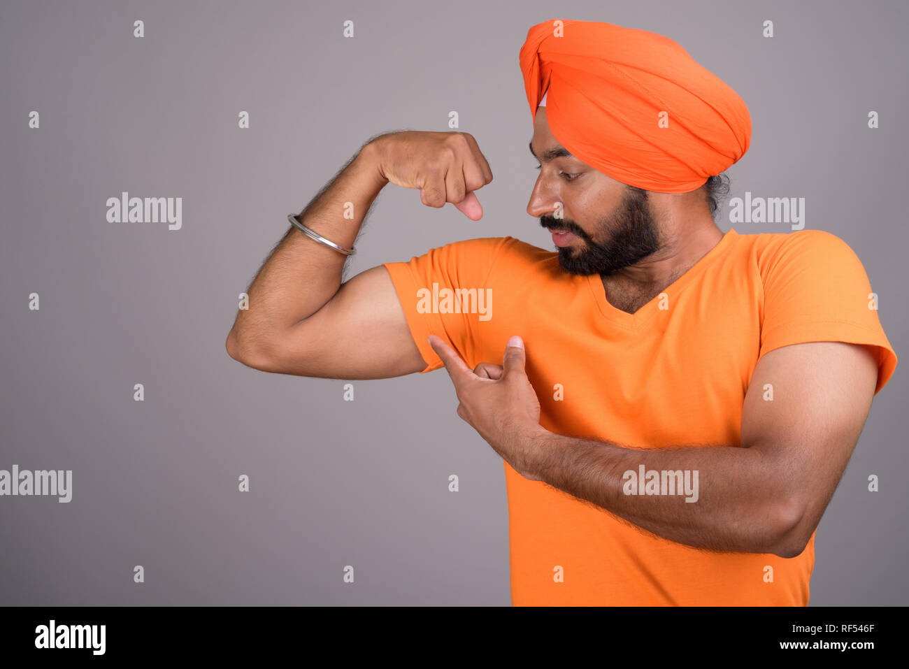 Indiano uomo Sikh indossando turbante e maglietta arancione Foto Stock