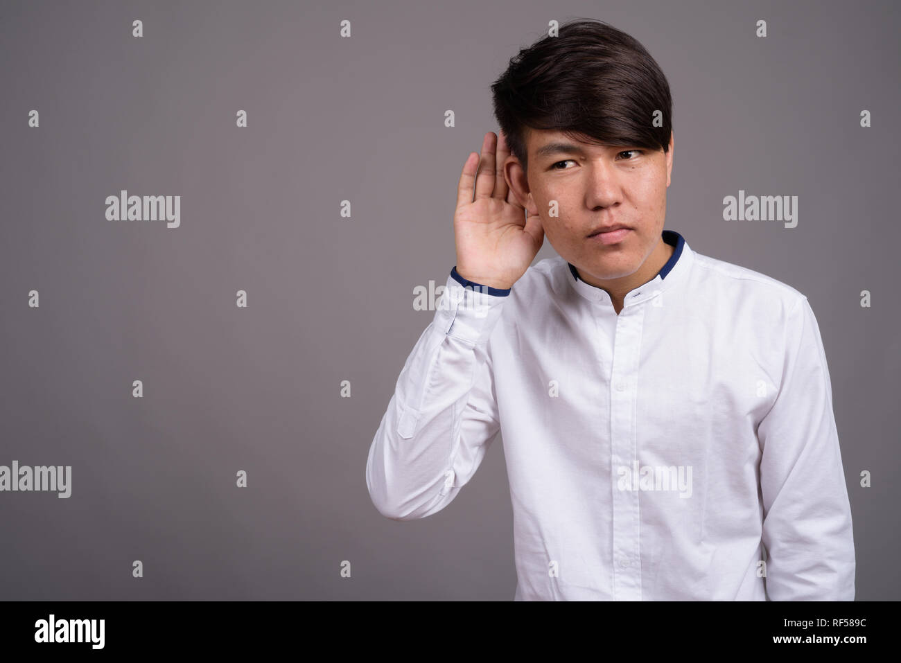 Giovani asiatici ragazzo adolescente contro uno sfondo grigio Foto Stock