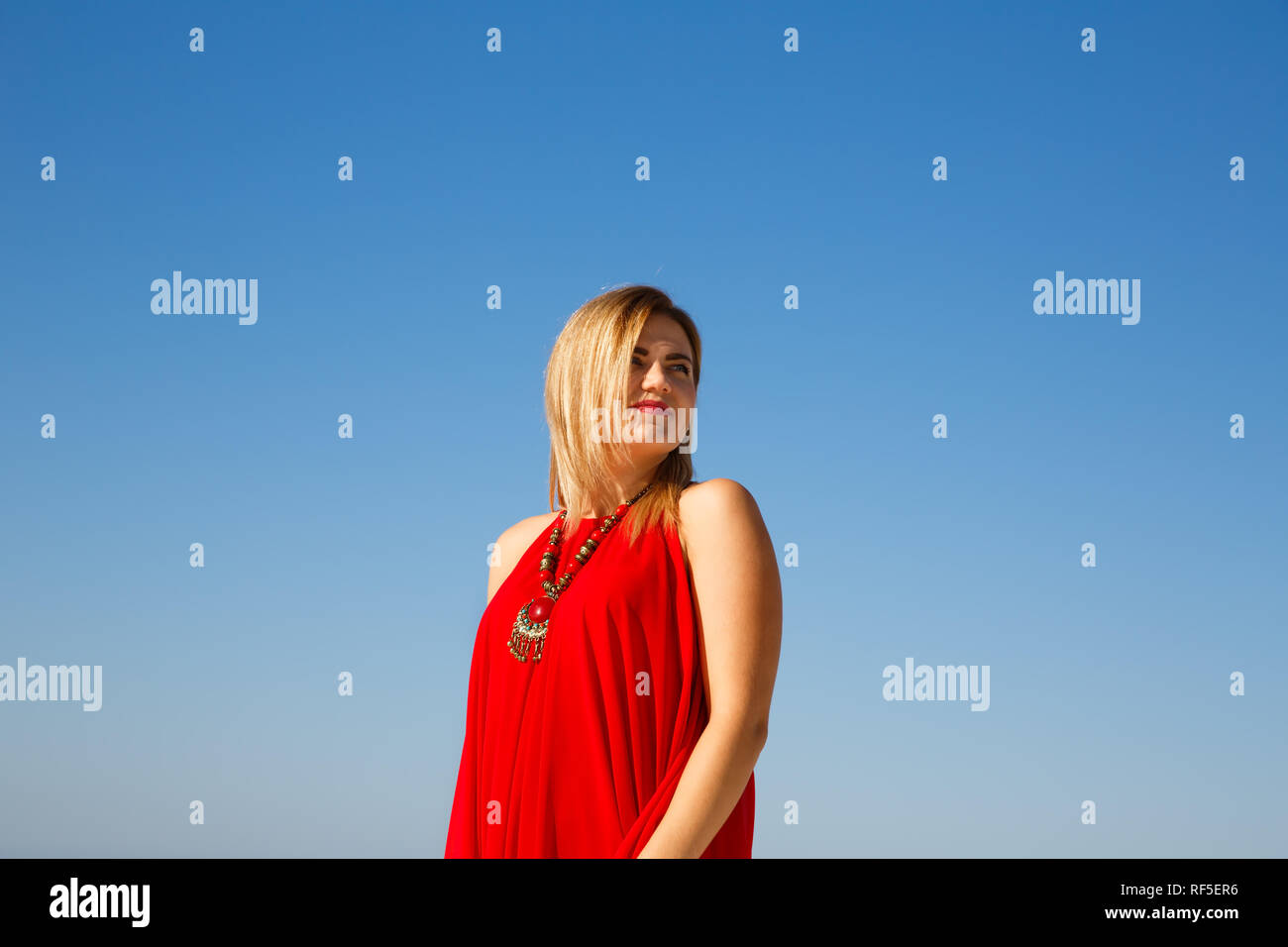 Donna bionda con collana in abito rosso. Foto Stock