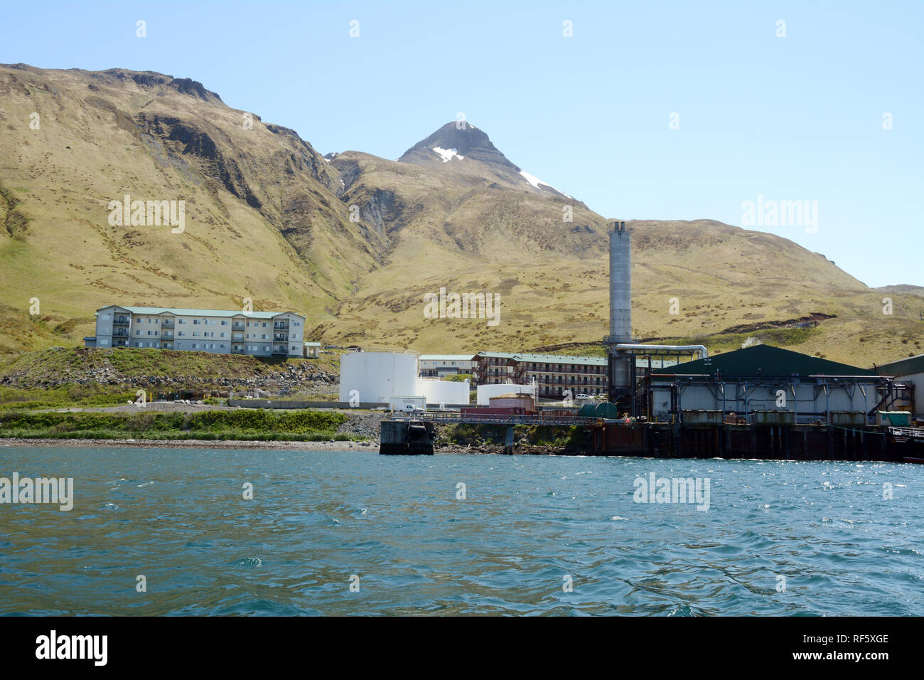 Un pesce allo stabilimento di trasformazione e i suoi lavoratori quarti sul mare di Bering al di sotto della piramide di montagna, nel porto olandese, Unalaska Isola, Alaska, Stati Uniti. Foto Stock