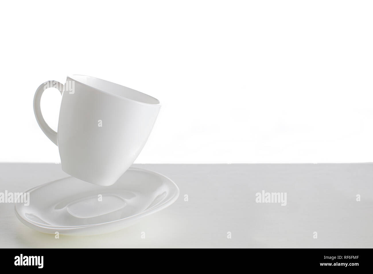 Tazza bianca con piattino in un salto su uno sfondo bianco. Jumping cup. Piatti volanti su sfondo bianco.piatti bianchi su sfondo bianco Foto Stock Tazza bianca con piattino in un salto su uno sfondo bianco. Jumping cup. Piatti volanti su sfondo bianco.piatti bianchi su sfondo bianco Foto Stock