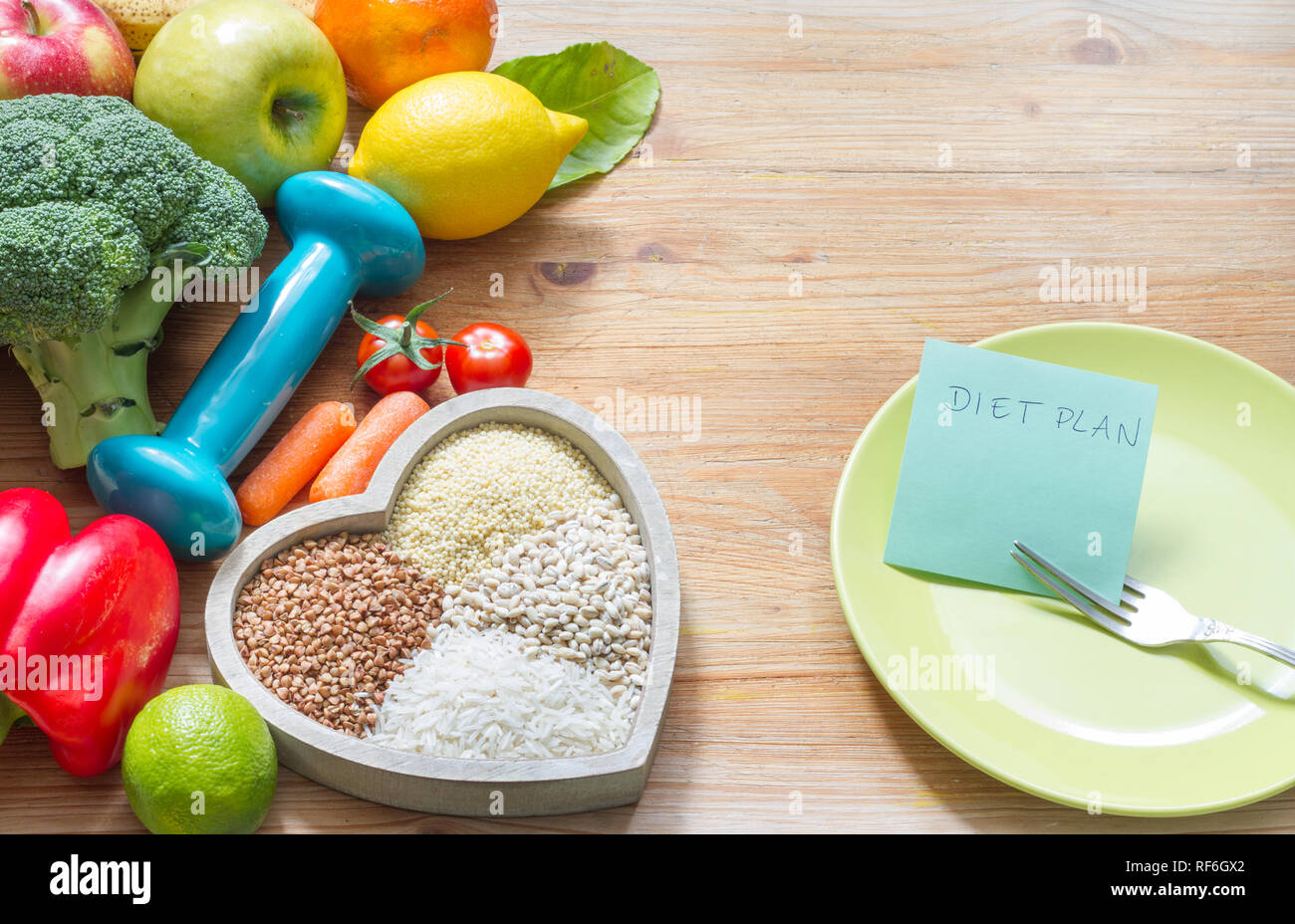 Programma di dieta e di stile di vita sano concetto con cibo vegetariano nel cuore e palestra dumbbell Foto Stock