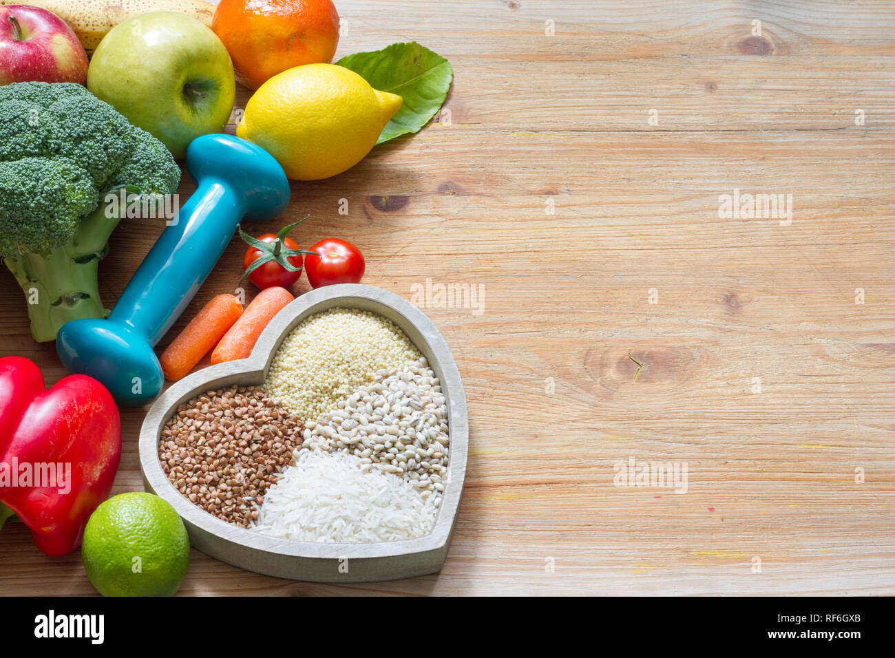 Programma di dieta e di stile di vita sano concetto con cibo vegetariano nel cuore e palestra dumbbell Foto Stock
