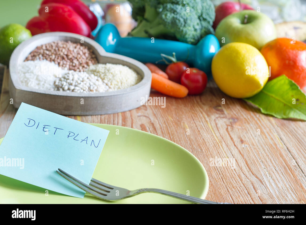 Programma di dieta e di stile di vita sano concetto con cibo vegetariano nel cuore e palestra dumbbell Foto Stock