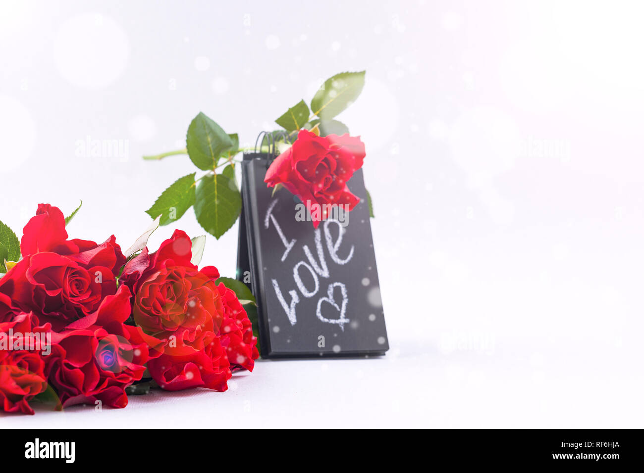 Un mazzo di rose rosse e una lettera con il testo dell'amore. Regali e  Fiori su uno sfondo bianco. Il concetto di il giorno di San Valentino e il  8 marzo in