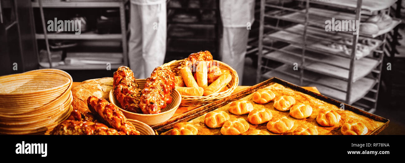 Michetta e cibo dolce su un tavolo mentre il maschio e la femmina baker lavora in background Foto Stock