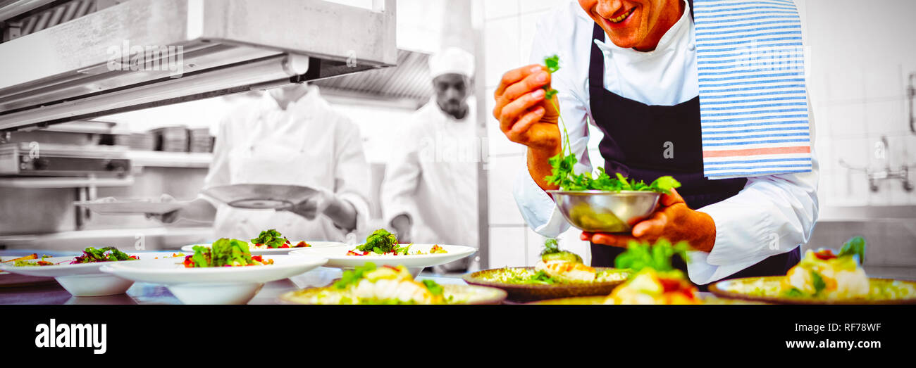 Felice chef guarnire antipasti piastre alla stazione di ordine Foto Stock
