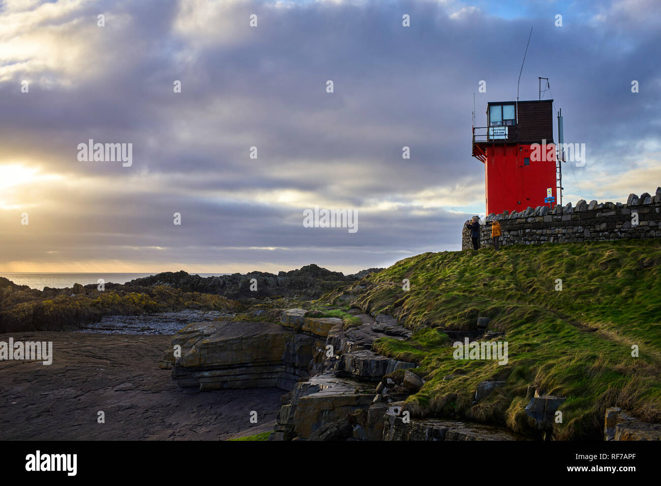Due donne di fronte ex guardia costiera Stazione di vedetta e torre webcam a Scarlett, Castletown, Isola di Man Foto Stock