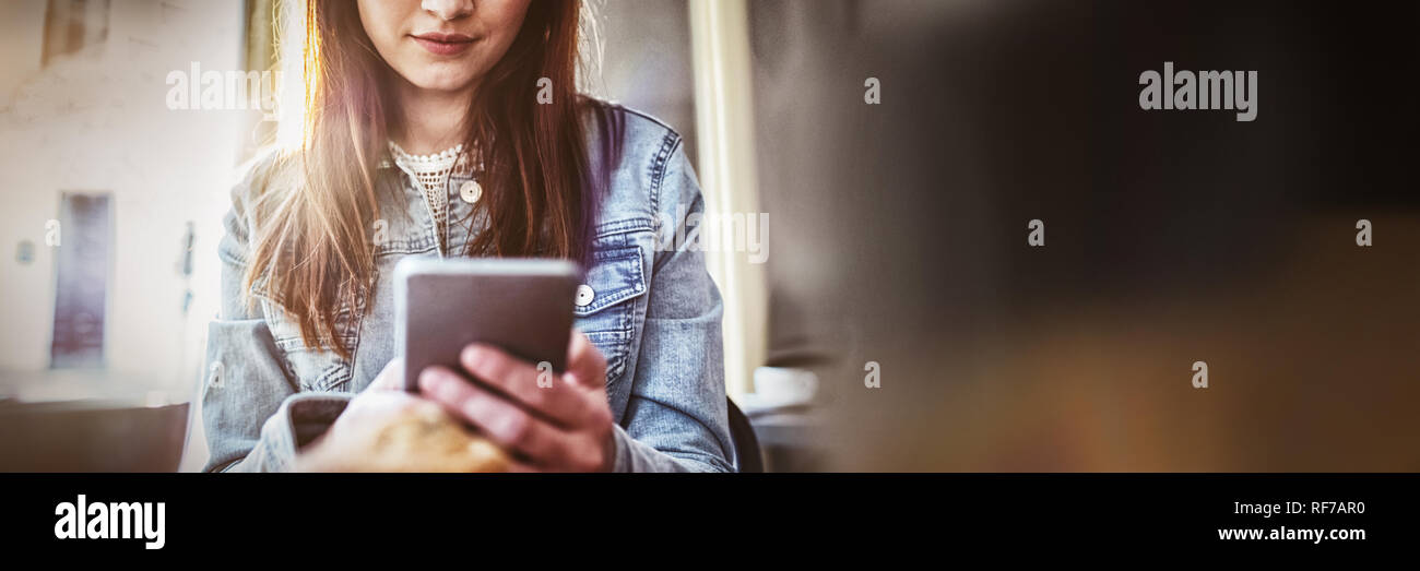 Bella donna utilizza lo smartphone al coffee shop Foto Stock