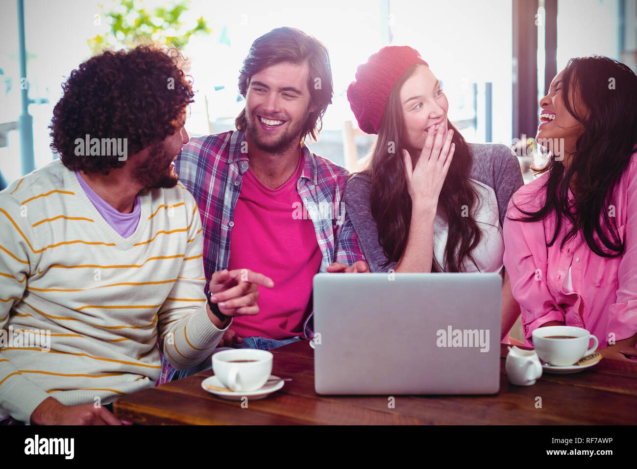 Ridere gli amici sorseggiando un caffè con laptop Foto Stock