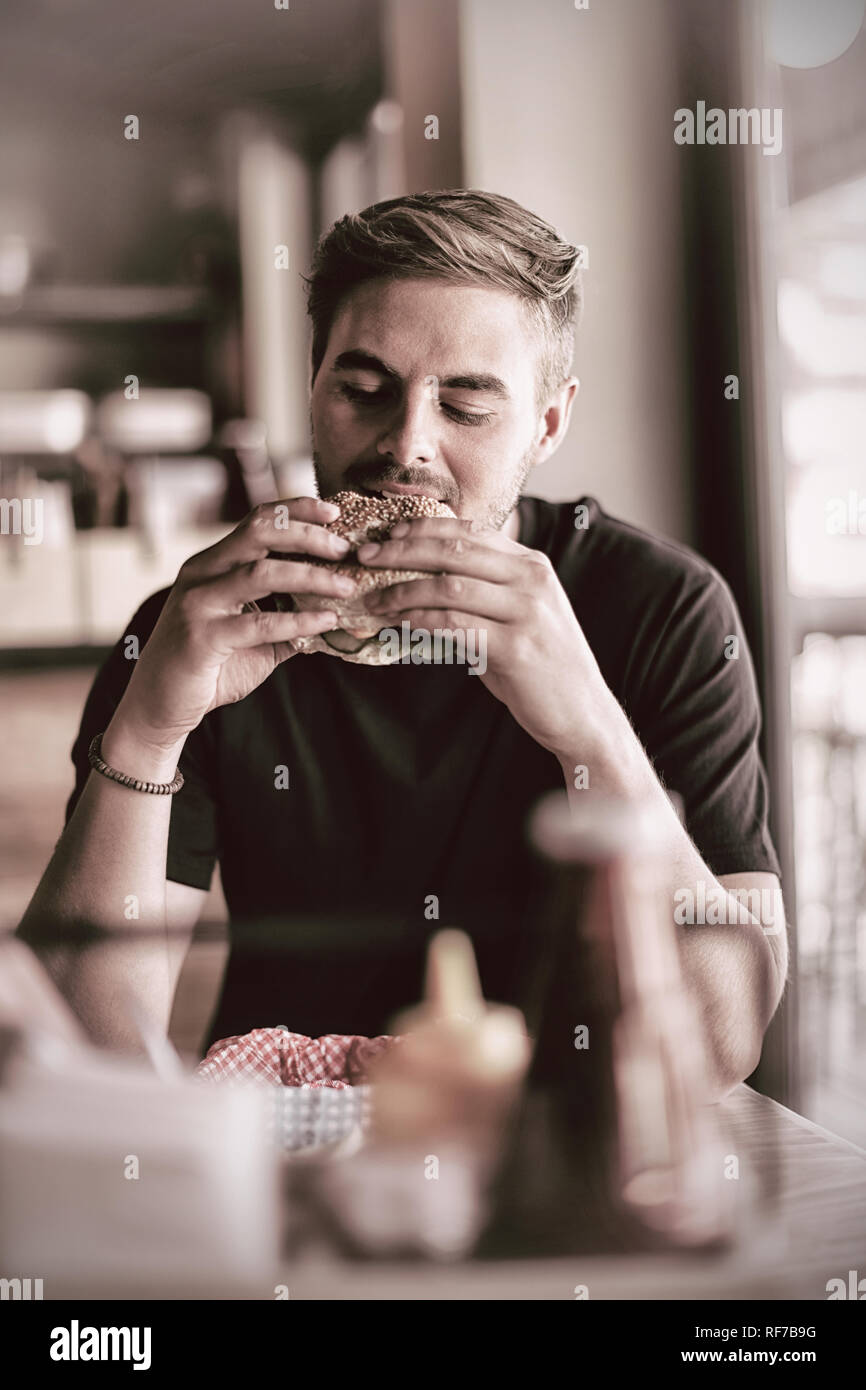 L'uomo mangiare hamburger Foto Stock