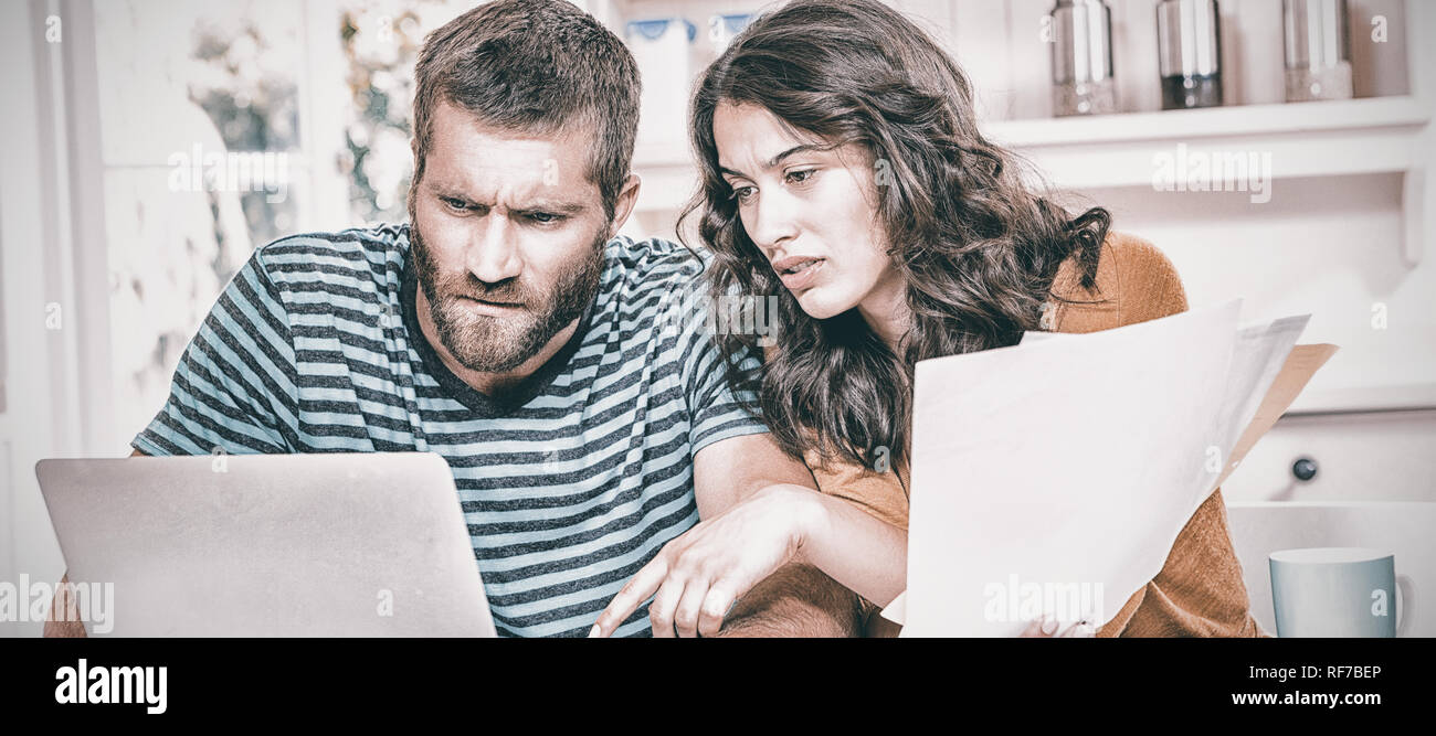 Paio di pagare le proprie fatture con notebook in cucina Foto Stock