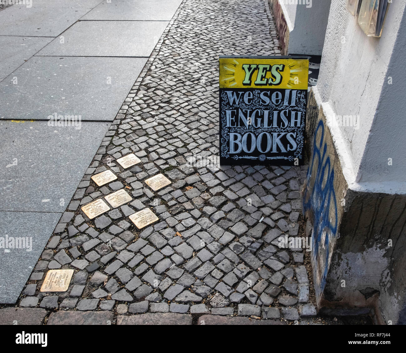 Berlino, Mitte. Street view con bronzo memorial pietre di inciampo sulla pavimentazione di ciottoli fuori Book shop Foto Stock