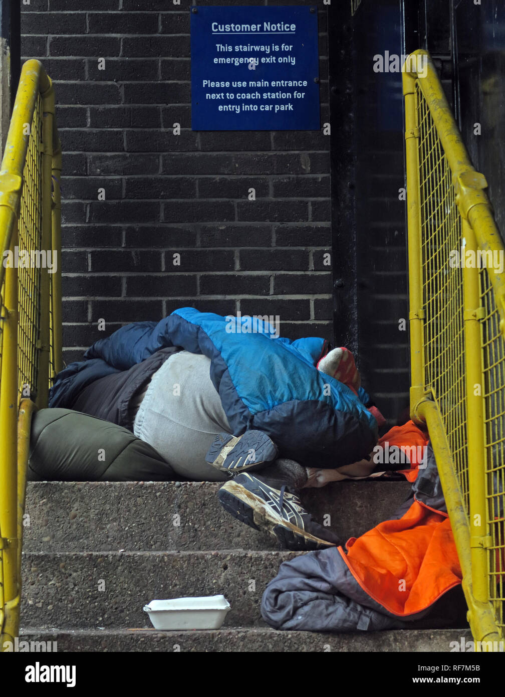 La persona senza dimora sleeping ruvida, in un parco auto scale, la stazione di autobus,Chorlton St, Manchester, M1 3JF Foto Stock