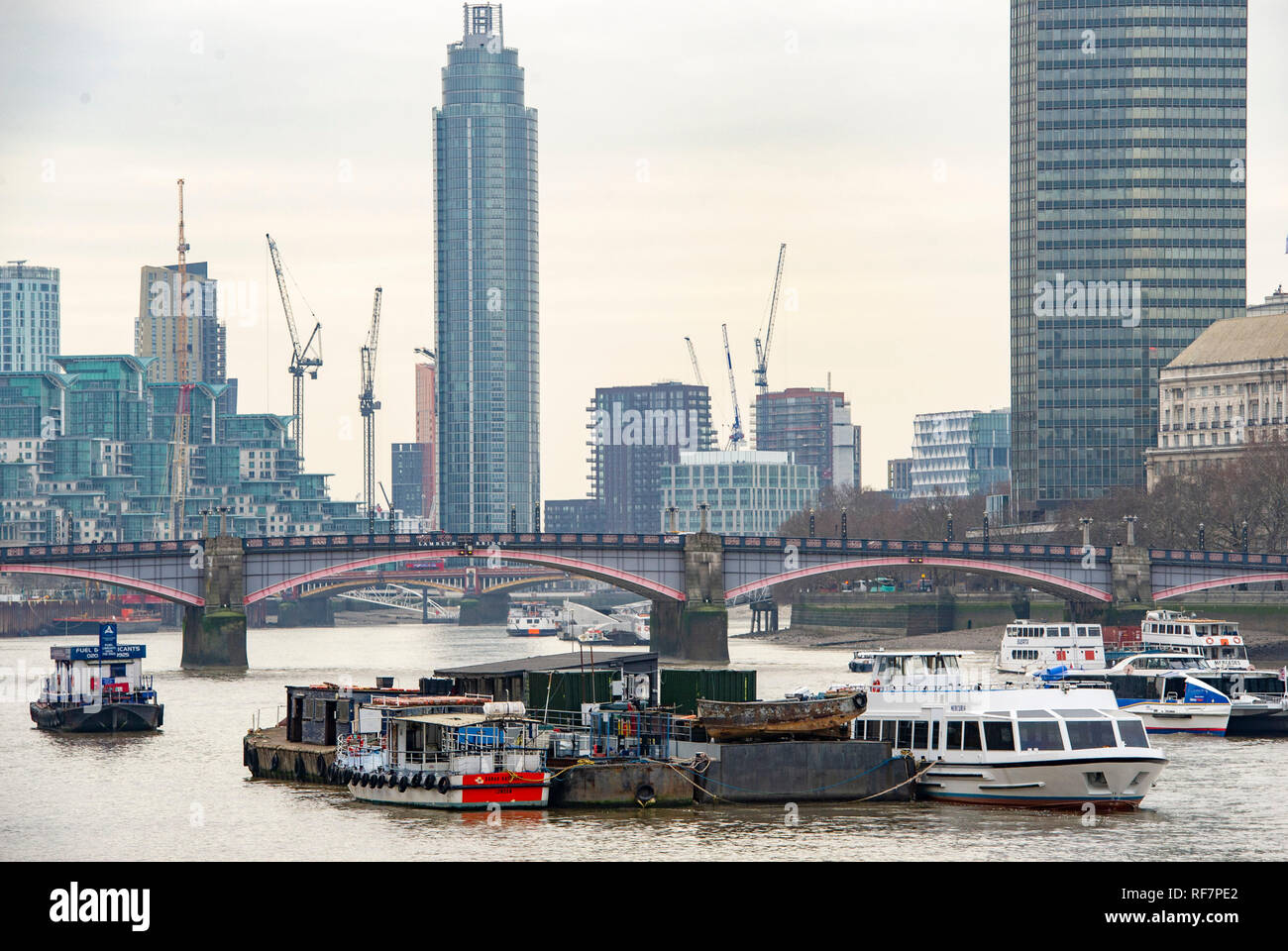 Barche da lavoro e chiatte sul Fiume Tamigi da Le Case del Parlamento a Londra REGNO UNITO fotografia scattata da Simon Dack Foto Stock