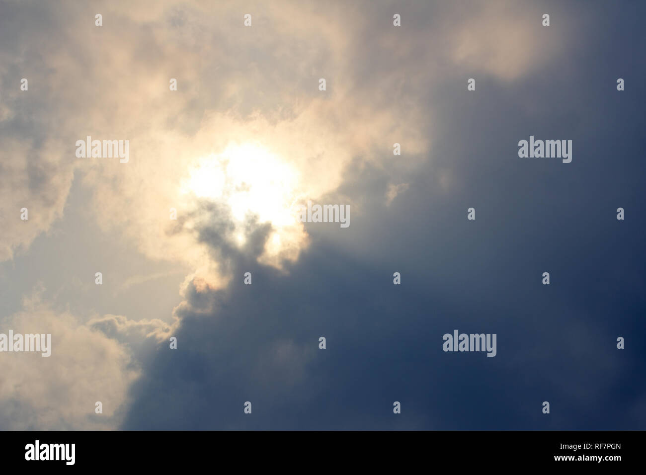 Sun emergenti dalle nuvole scure - brilla in alto nel cielo Foto Stock
