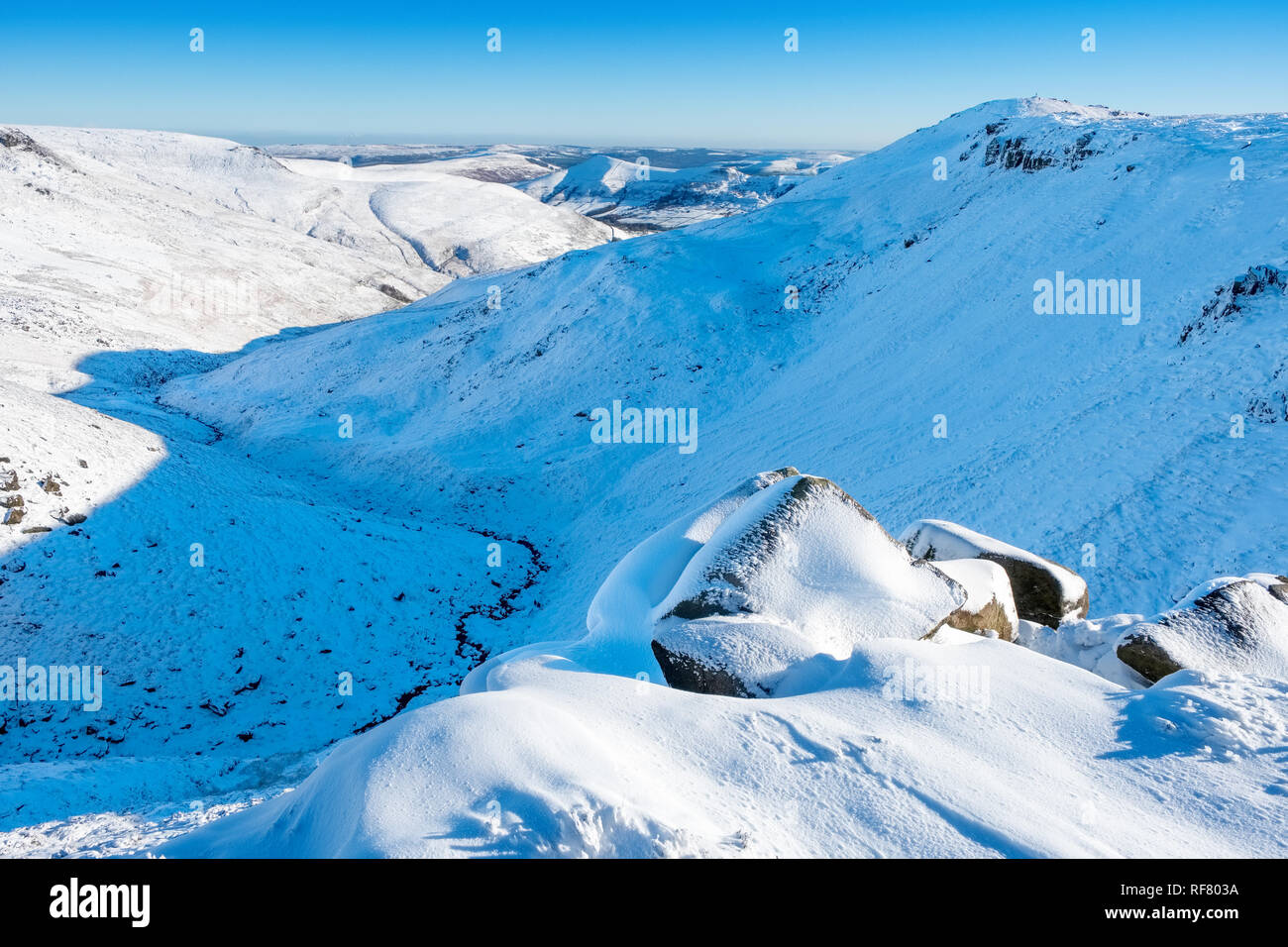 Kinder Scout nel Parco Nazionale di Peak District, UK, in inverno la neve. Visualizza in basso Grindsbrook Clough Foto Stock