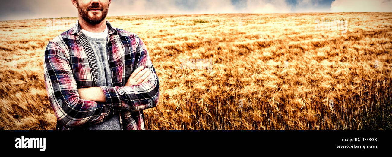 Ritratto di agricoltore in piedi con le braccia incrociate nel campo Foto Stock