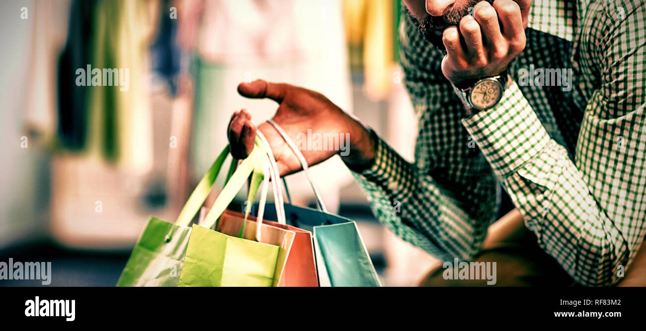 Annoiato uomo con borse per lo shopping e la donna dal portabiti Foto Stock