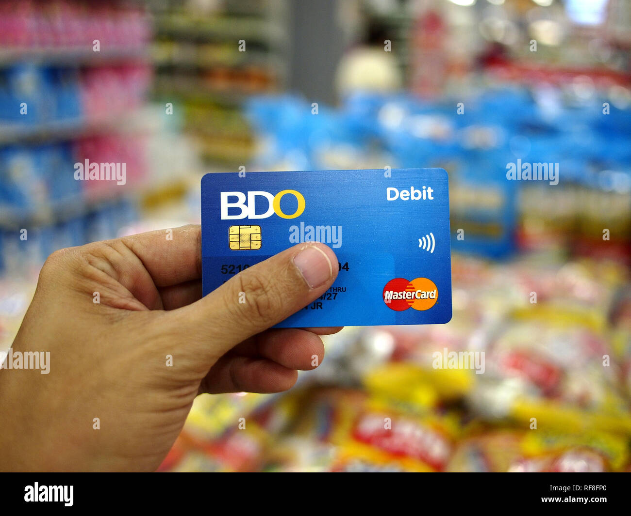 ANTIPOLO City, Filippine - 15 gennaio 2019: la mano di un cliente in possesso di una carta di credito all'interno di un negozio di alimentari. Foto Stock