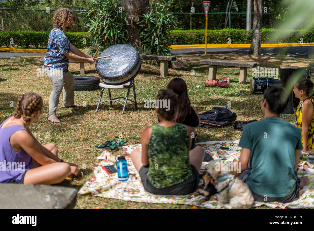 Un uomo giocando un giapponese taiko drum di vecchi pneumatici e del nastro per condotti per una piccola folla in un bellissimo parco Foto Stock