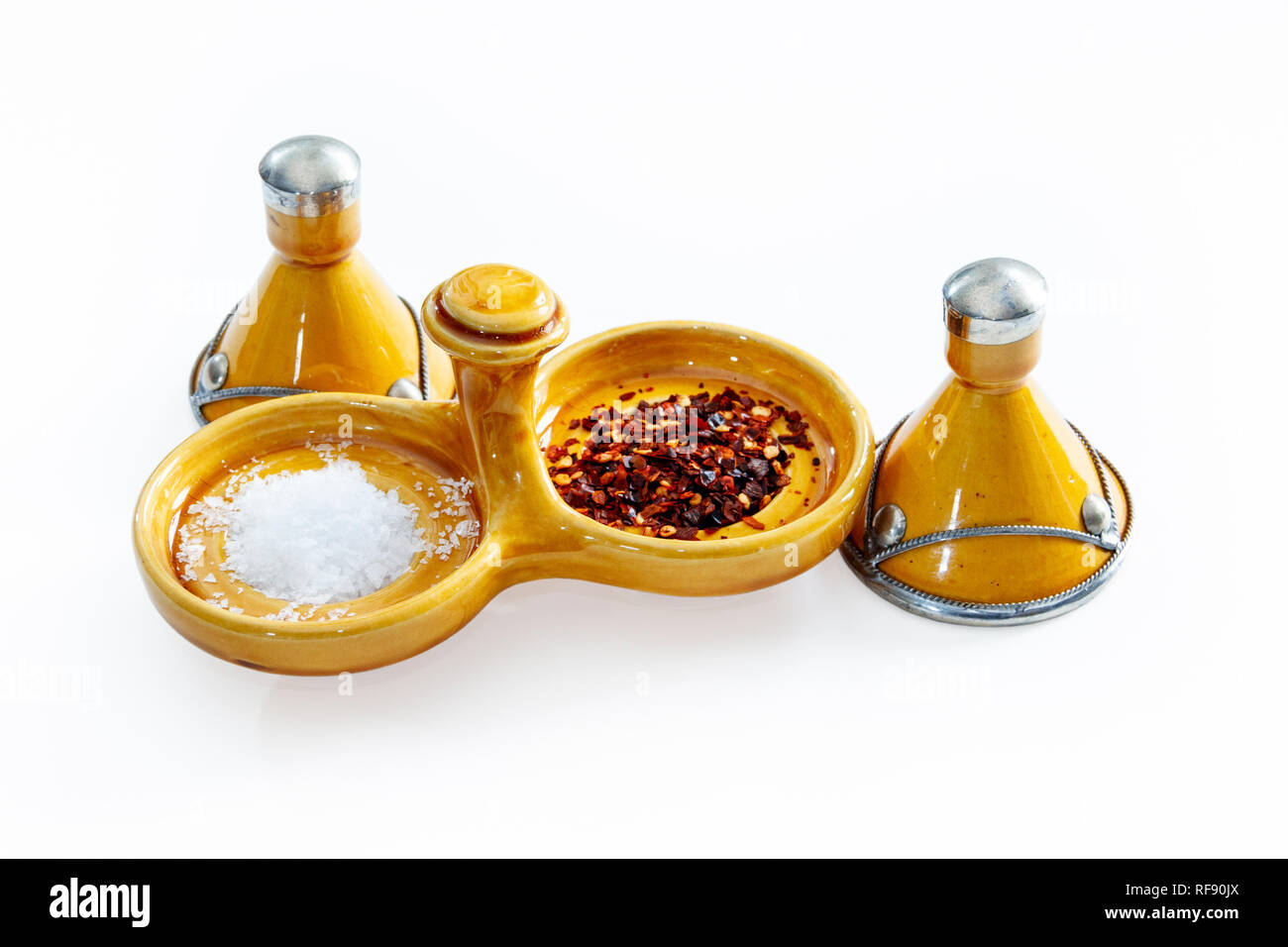 Arancione tradizionale marocchino smaltata ceramica sale e pepe piatto con sale marino e peperoncino in scaglie su sfondo bianco Foto Stock