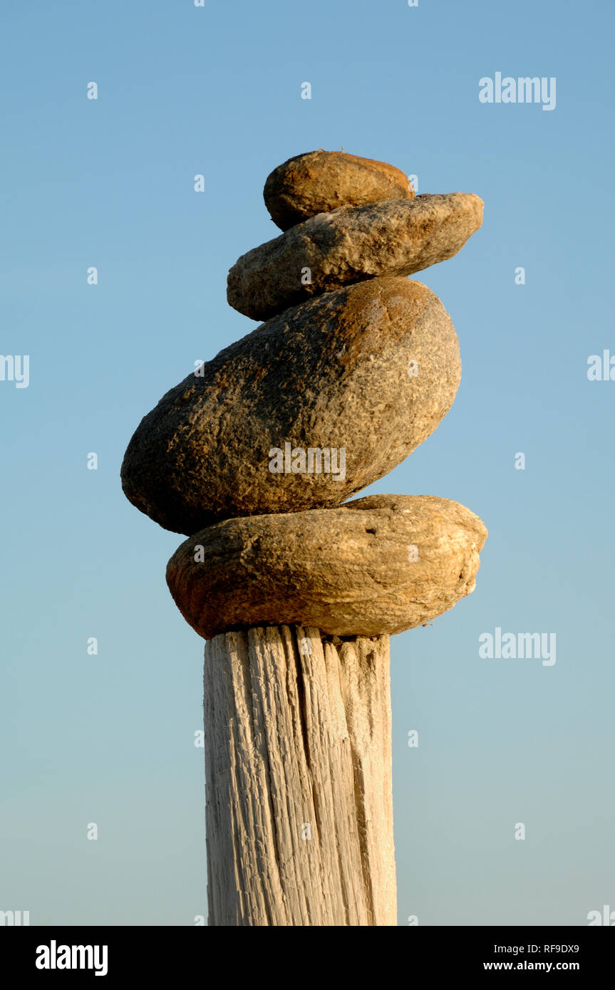 Bilanciamento di roccia, pietra bilanciamento, Stack di pietra o roccia Stack Arte di terra sul legname Post nella Camargue Provenza Francia Foto Stock