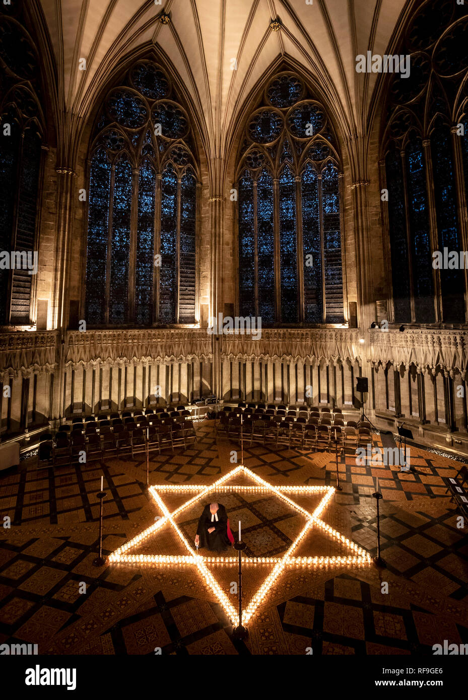 Cancelliere Canon Christopher Collingwood aiuta sei luce di centinaia di candele a forma di stella di Davide, in memoria di più di 6 milioni di ebrei uccisi dai nazisti durante la Seconda Guerra Mondiale a York Minster in York. Foto Stock