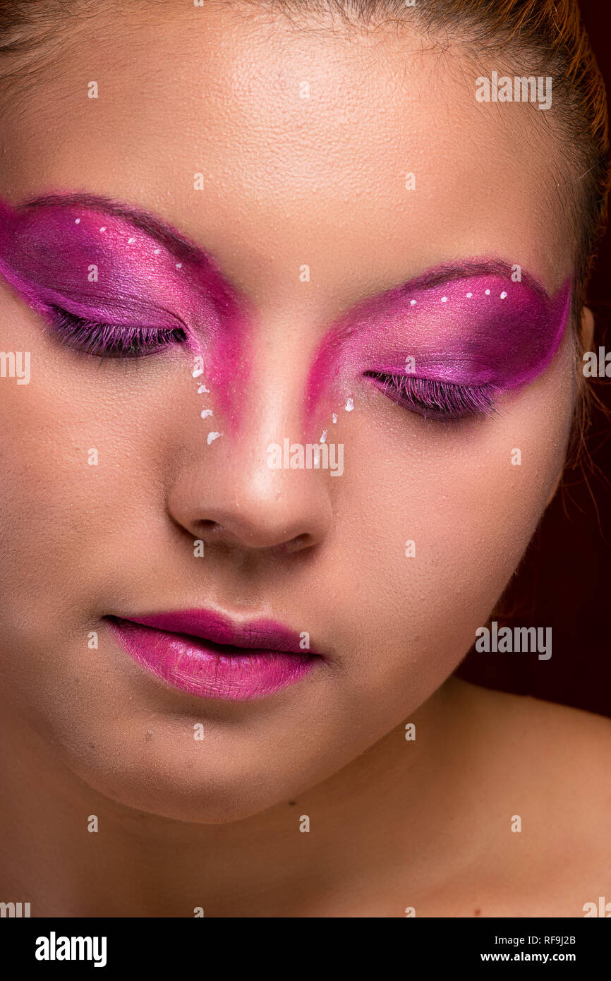 Giovane e bella ragazza ritratto, con viola e rosa trucco, closeup, gli occhi chiusi guardando verso il basso Foto Stock