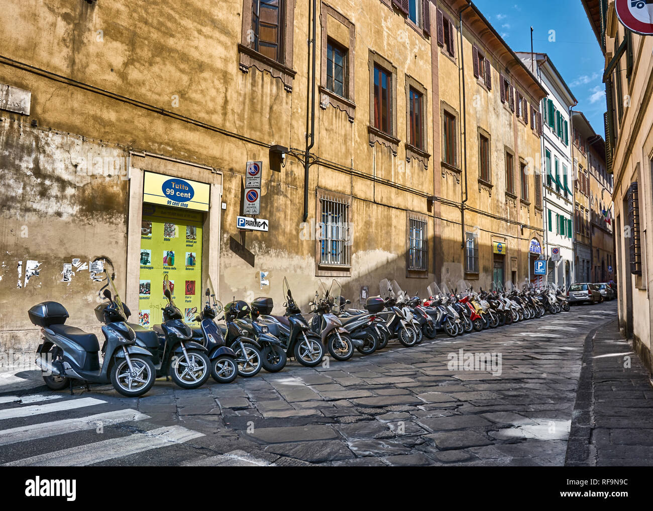 Moto parcheggiate su strada stretta a Firenze, Italia, e circondato da vecchi appartamenti. Foto Stock